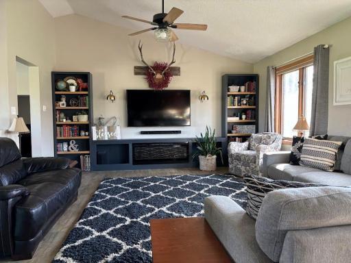 The spacious living room with vaulted ceiling has built in shelves with modern fireplace & place for TV.