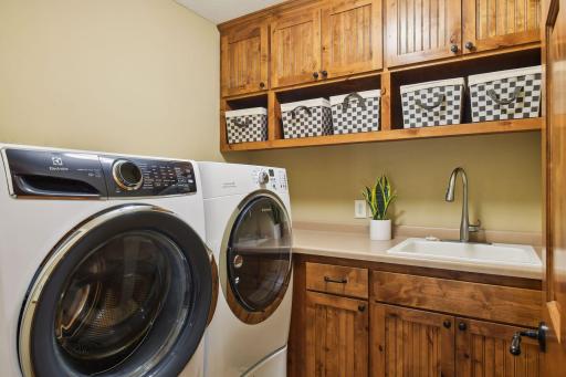 Upper level laundry with washer and dryer on pedestals and plenty of cabinets and cubbies for extra storage