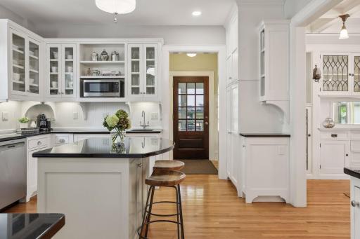 Kitchen with additional cabinetry and storage and glass front door leading to the sunroom / screen porch.