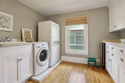 Upper level laundry room with front loading washer and dryer as well as built-in cabinets for storage, sink, and drying system.