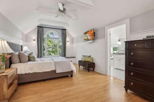 WOW! This third story primary bedroom suite is a 10! High vaulted ceilings, tall windows with classic details and hardwood floors.
