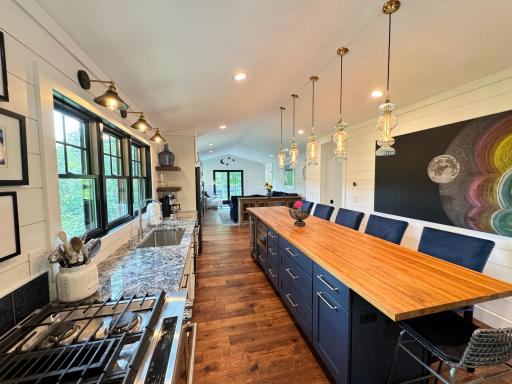 Two tone cabinets, large butcher block center island, gas range, and so much natural light in the second wing area