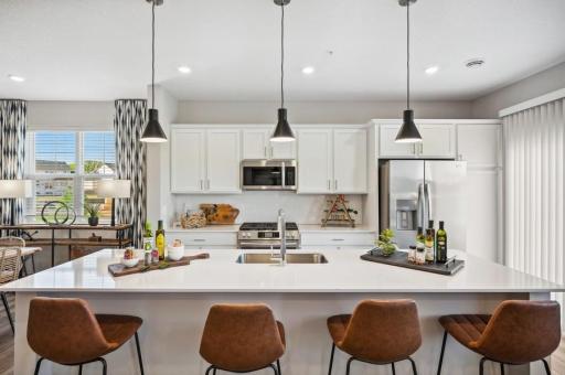 (Photo of decorated model, actual home's finishes will vary) This spacious kitchen features a large center island, quartz countertops, LVP floors and more!