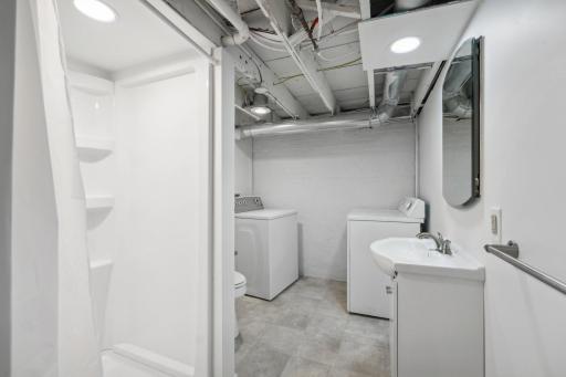 Basement Bthroom with washer, dryer, sink, shower, toilet in it.