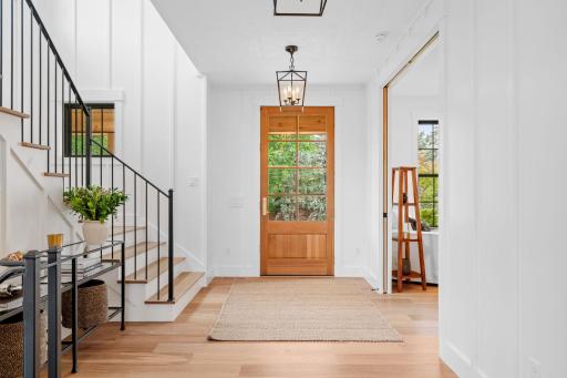 The grand entry of this home is a breathtaking introduction to its elegant interiors, designed to welcome guests with style. Upon entering, you are greeted by soaring ceilings adorned with chandeliers that cast a warm, inviting glow.
