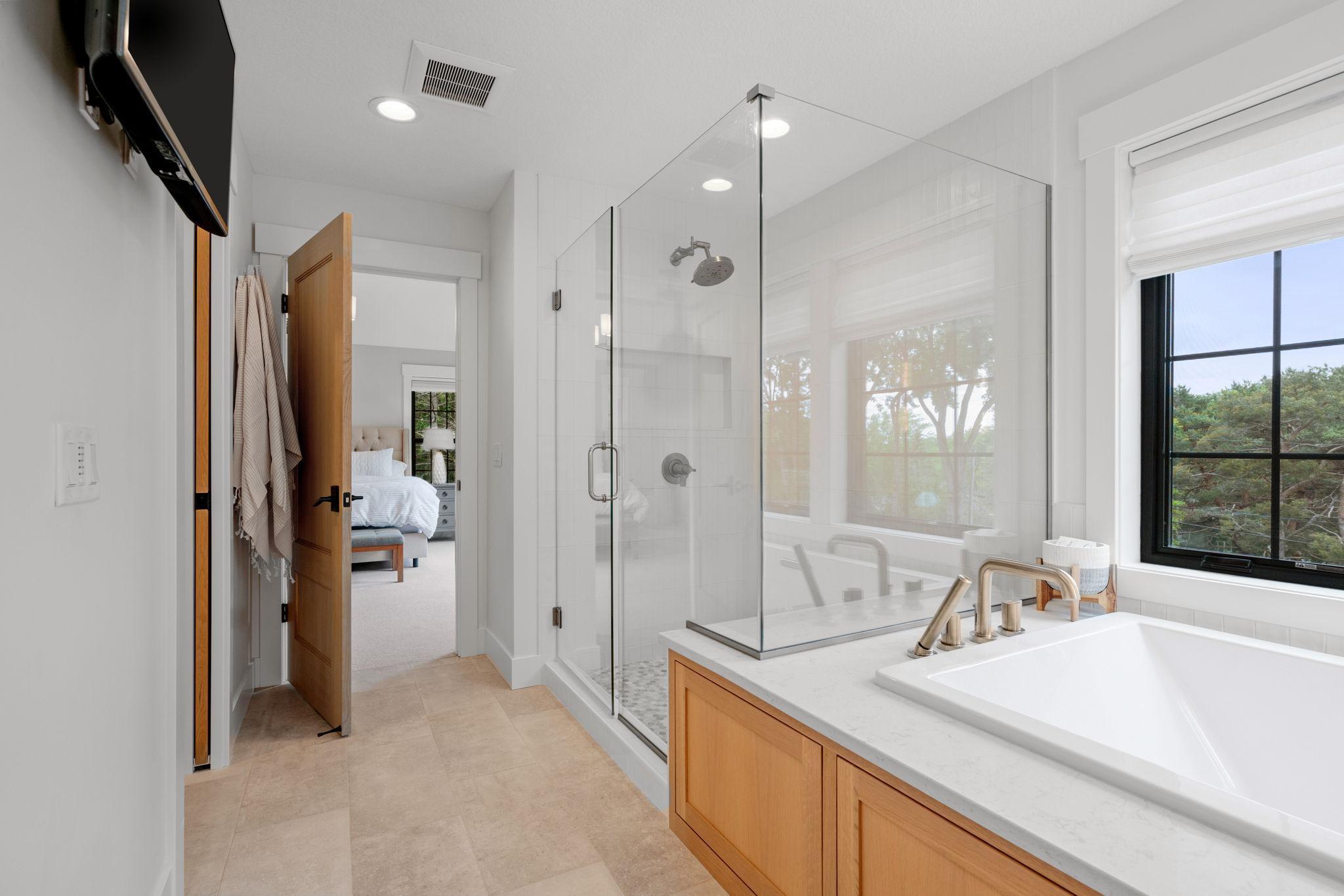 At the heart of this sanctuary, discover a separate tiled shower, a marvel of modern design. Encased in sleek glass walls and adorned with custom tile work.