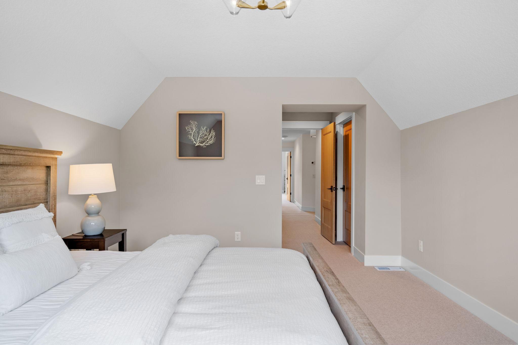 In this first bedroom, you're greeted by an oasis of comfort and style. Soft natural light spills through the windows, casting a warm glow over the elegant furnishings.