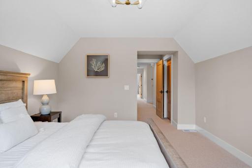 In this first bedroom, you're greeted by an oasis of comfort and style. Soft natural light spills through the windows, casting a warm glow over the elegant furnishings.