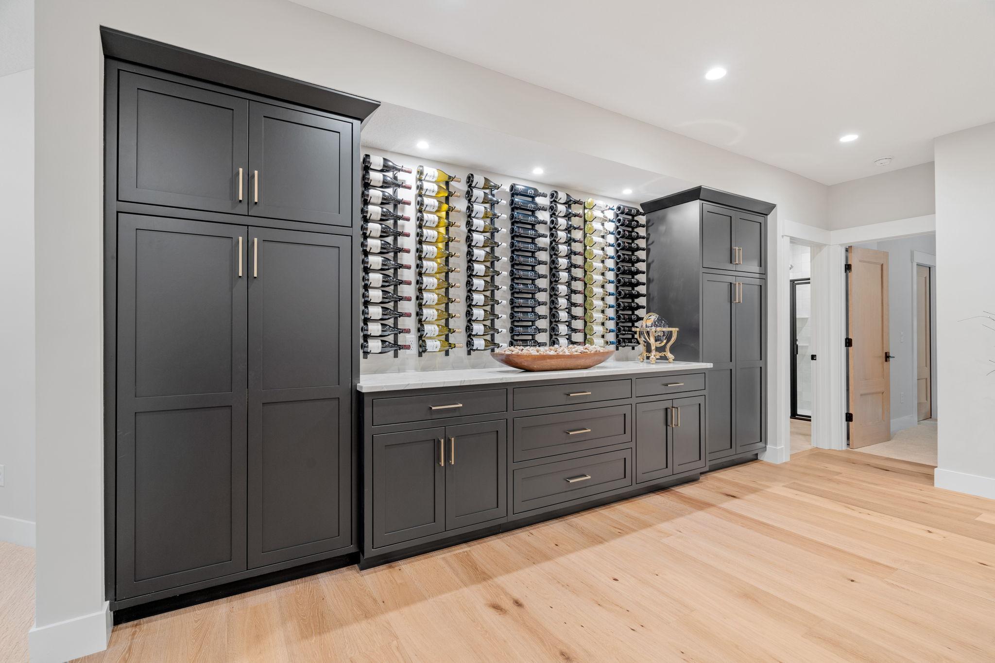 A buffet area with a quartzite countertop and additional built-in cabinets offers even more storage and serving space, making this lower level perfect for hosting parties or casual get-togethers.