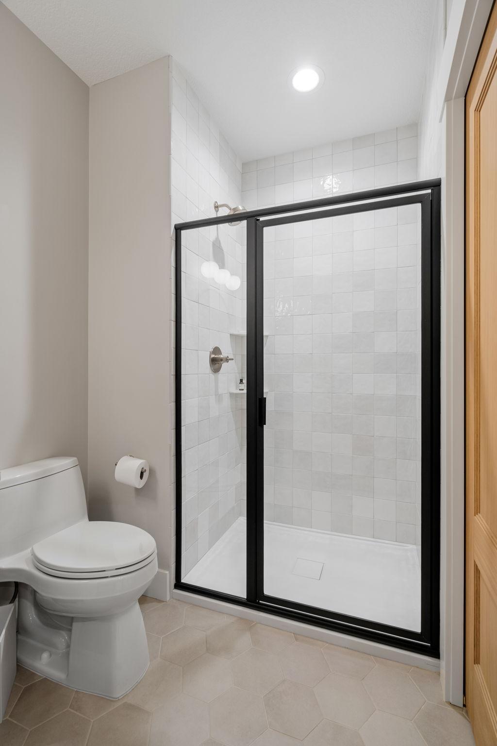 Lower level 3/4 bath has a sleek and sophisticated shower, boasting a stunning tile surround that exudes contemporary charm.