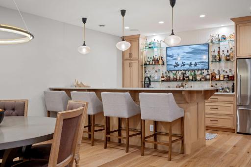 The bar area in the lower level features quartzite counters, a Bosch dishwasher, a wine fridge, and a full-size counter-depth refrigerator.