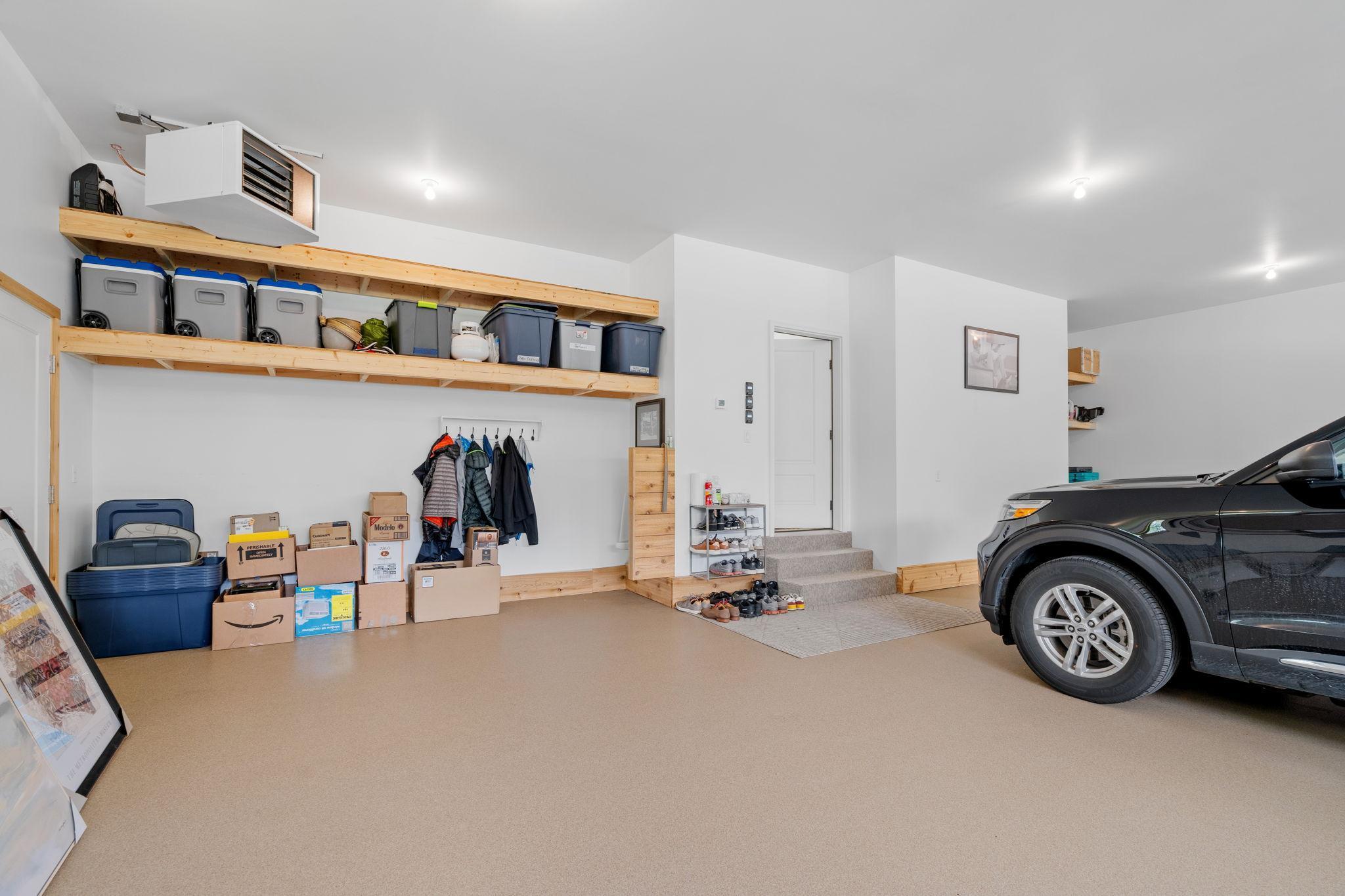 The garage boasts a generous 11-foot ceiling, accommodating a variety of vehicle sizes and offering ample vertical storage potential. The custom quartz epoxy floor is durable and an easy-to-clean surface that stands up to heavy use.