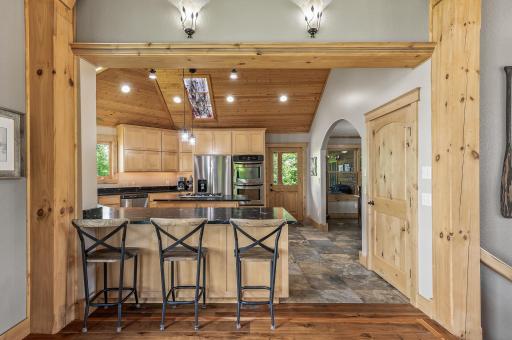 View from the great room into the open kitchen with breakfast bar seating at quartzite countertops.