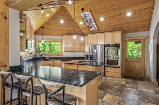 The kitchen is massive with in-ceiling-stained glass lights, quartzite countertops, tile flooring, custom maple cabinets, large pantry, double oven, a new fridge, disposal and microwave.