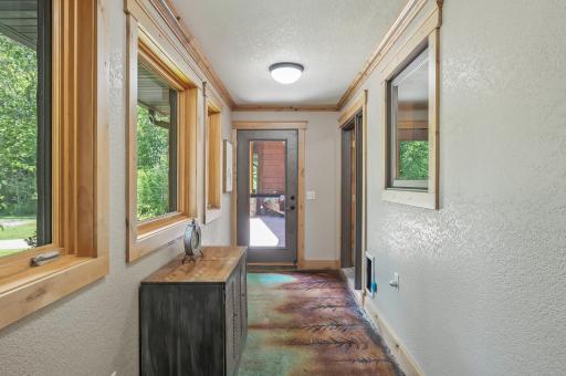 The breezeway accessing the garage and the front porch as front facing windows and colored concrete floors.