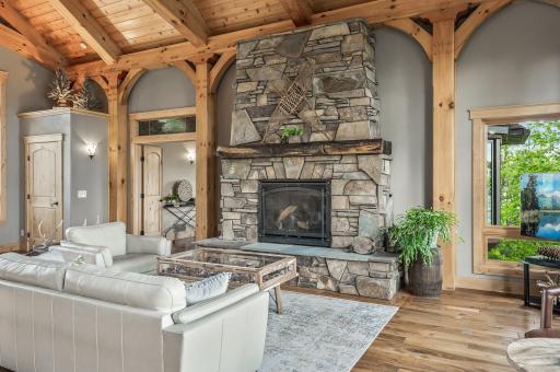 The centerpiece of the great room is the gas fireplace, adorned with a floor-to-ceiling stone surround and a rustic wood beam mantle, providing both warmth and a charming focal point.