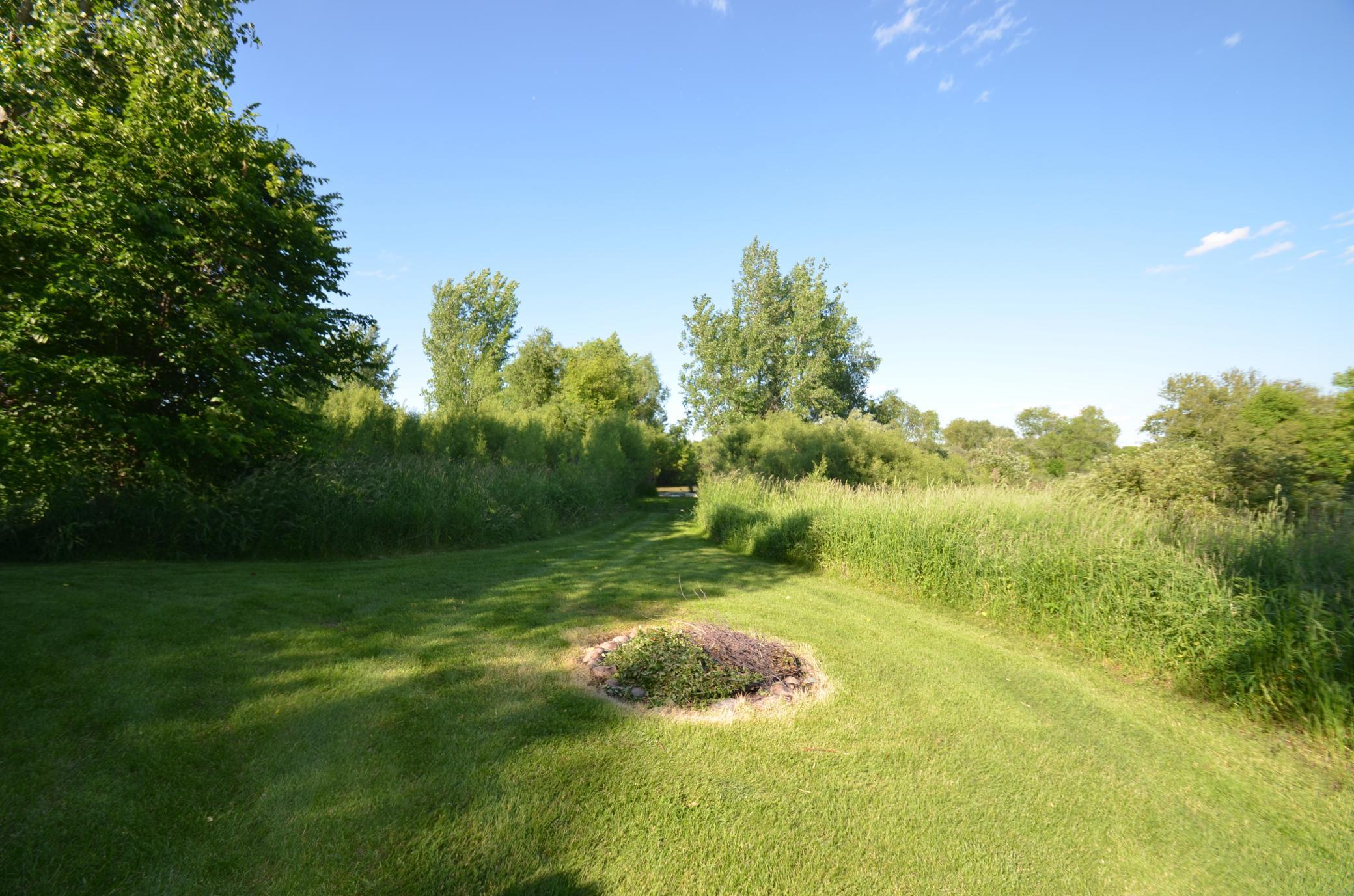 The firepit in the backyard is at the head of the path to the pond.