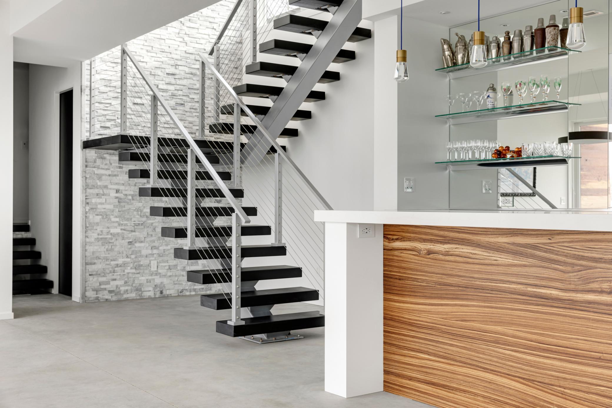 The floating staircase descends to the full bar/kitchen in the lower level.