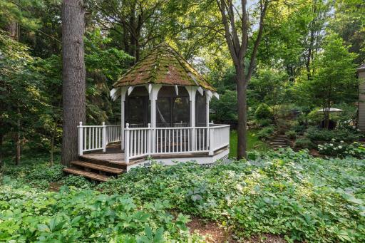 This quaint gazabo is tucked off to the side of the house surrounded by lush plantings.