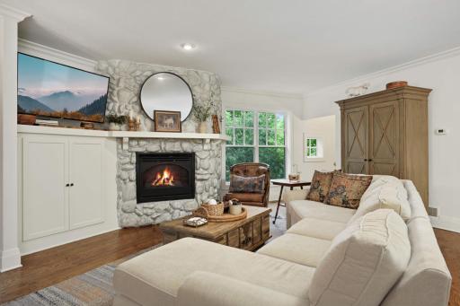 The family room features a practical and elegant enameled cabinet space for components and the fieldstone surrounded fireplace adds warmth and charm.