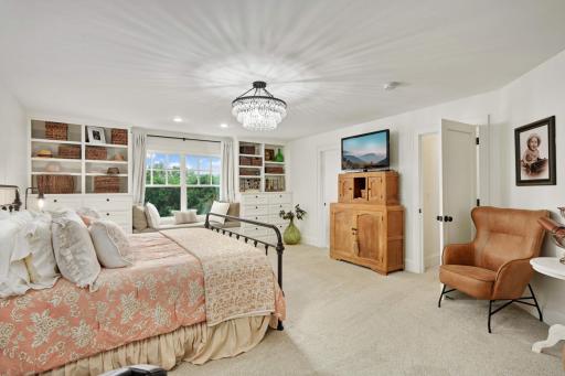 The primary suite is a space to be envied. Walls of custom built in cabinetry flank the charming bench seat makes a dresser nearly non-essential.