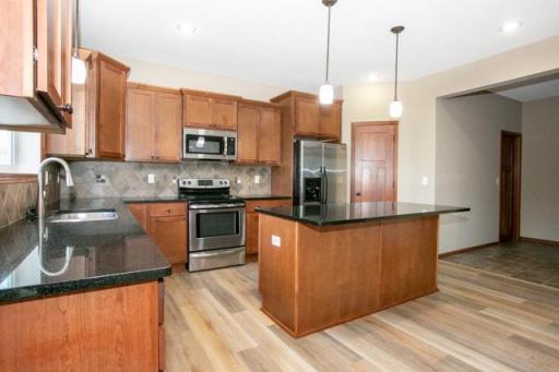 Open kitchen with stainless steel appliances, granite countertops and new flooring