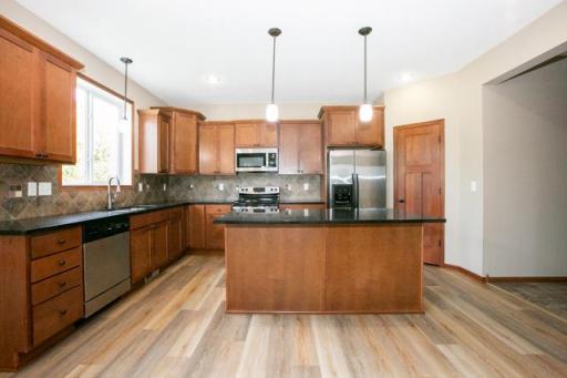 Open kitchen with stainless steel appliances, granite countertops and new flooring