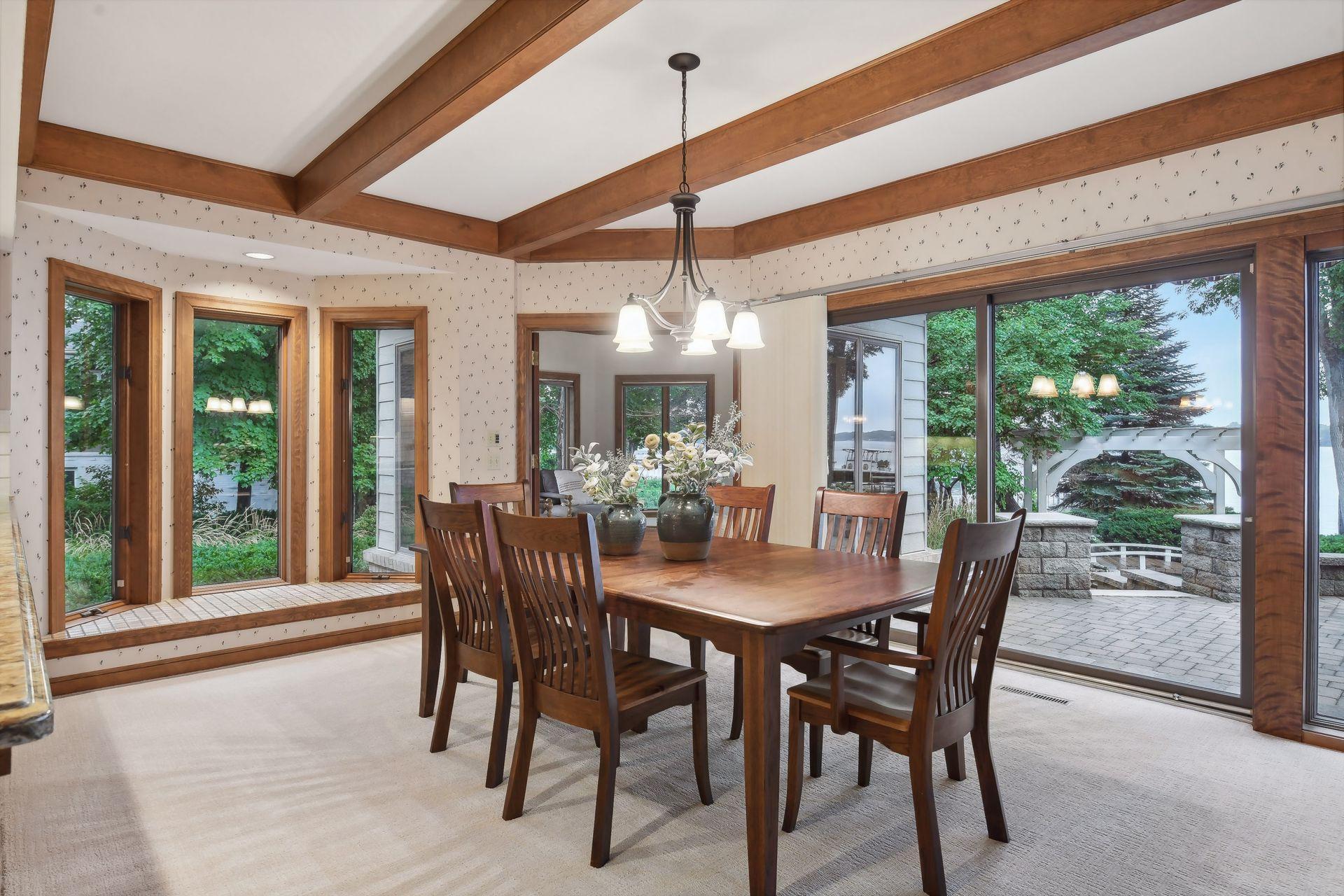 Informal dining room with wood beamed ceiling, bay window and lakeside wall of glass.