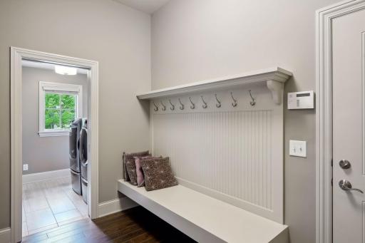 Convenient bead board wall with jacket hooks and sitting bench helps keep all things in their proper place