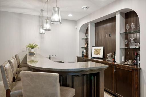 Impressive wet bar includes a beverage refrigerator, microwave and sink plus an inset cove shelving