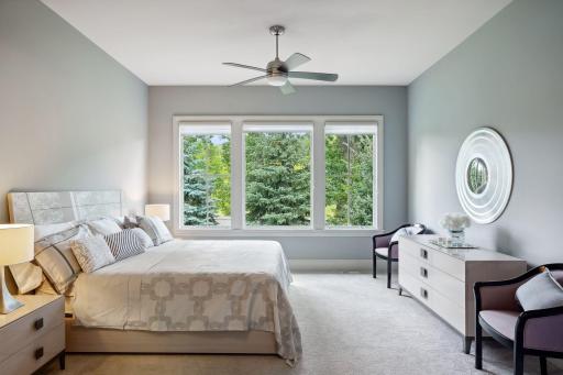 Main floor primary bedroom looks over the lushly landscaped and private back yard