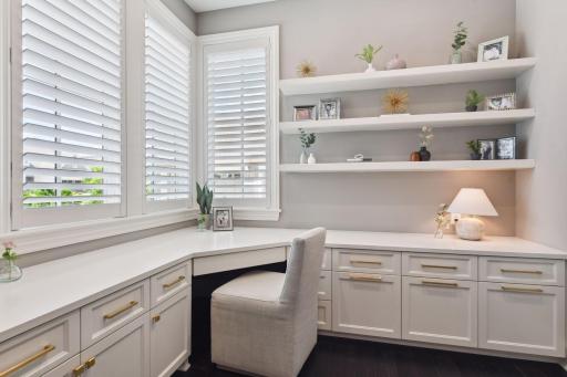 Work from home in this gorgeous office featuring plantation shutters, custom built-in cabinetry and floating shelves.