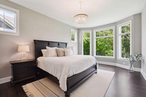Private primary suite with spacious spa-like bath, luxury custom closet, and large bay window.