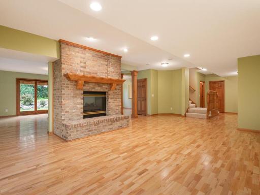 Lower level Amusement Room area features wood flooring and double-sided gas fireplace.