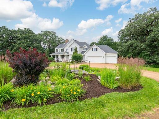 Attractive perennial garden with bridge in the center of the circle driveway.