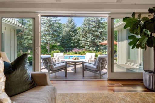 Wall of windows slides open to seamlessly blend the living room with the outdoor entertaining spaces, creating a perfect indoor-outdoor flow for gatherings and relaxation