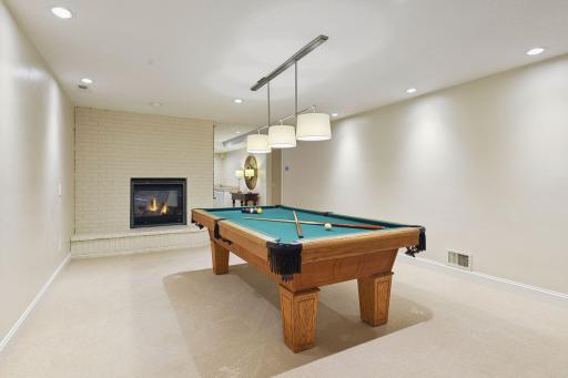The expansive lower level features two large entertainment rooms anchored by a double-sided gas fireplace, creating a warm and inviting atmosphere. One side is a perfect hangout for a game of pool