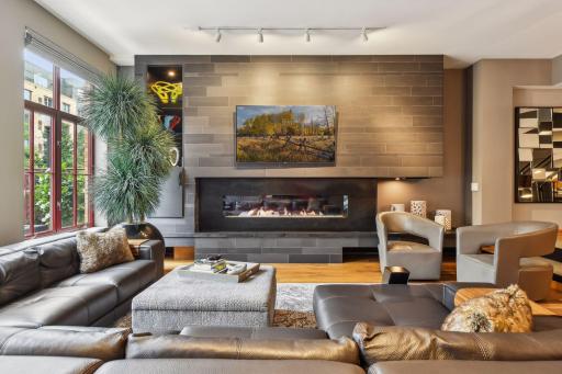 The unique modern feature wall integrates a contemporary gas fireplace, cabinetry to house A/V equipment, art display, and generous space for any size TV one could want