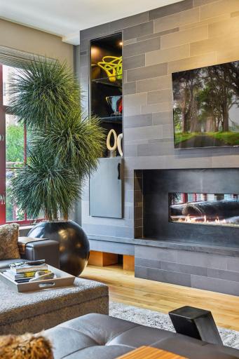 The unique modern feature wall integrates a contemporary gas fireplace, cabinetry to house A/V equipment, art display, and generous space for any size TV one could want