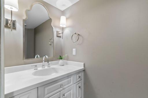 Main Level Powder Room features enameled vanity cabinet and modern tile flooring