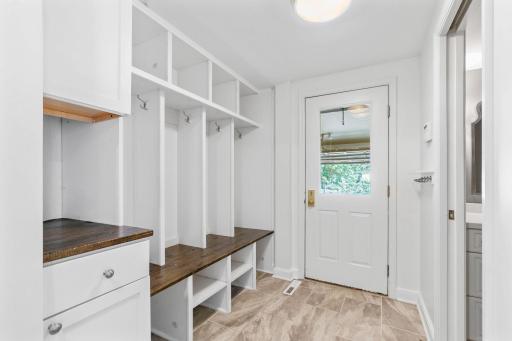 Mud Room offers Built-in storage lockers w/ hooks, cubbies and a drop station, modern tile flooring and a partial glass entry door w/ garage access