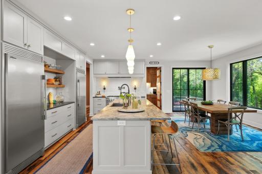 Separate Frigidaire refrigerator and freezer, a Fisher and Paykel drawer dishwasher, and a large center island with breakfast bar seating.