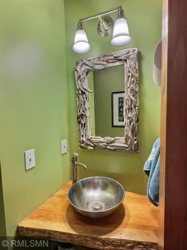 Just off the foyer is a half bathroom with live edge wood countertop and open shelving, perfect for visitors.