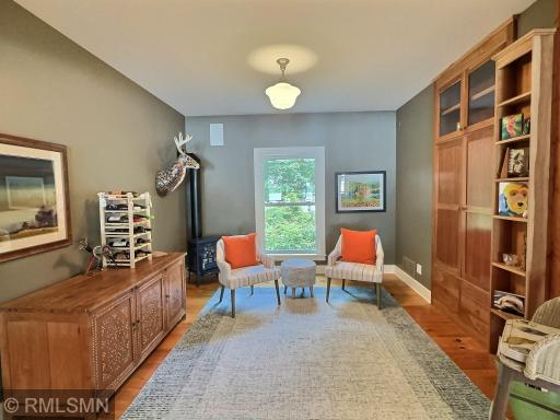 Just off the living room, the sitting room has wood flooring and a custom built-in desk and shelves to the right.