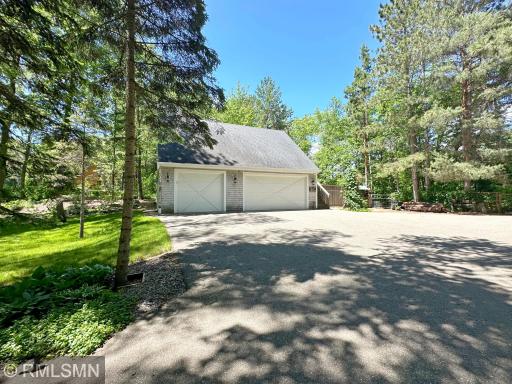 Towering trees create a lovely, canopied driveway welcoming you to this lake home, view of the triple detached.