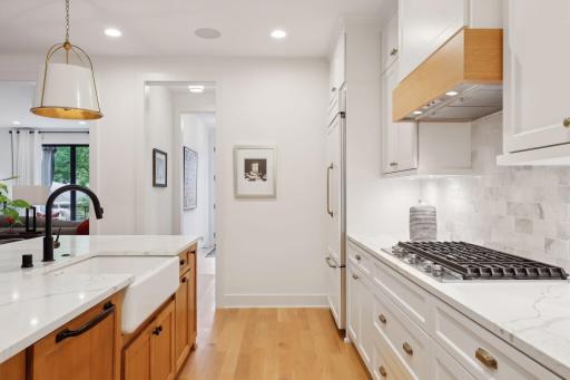 Custom white oak wrapped Zephyr range hood, center island cabinetry, and farmhouse sink.