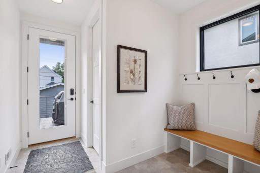 Mudroom with large coat closet, tile floors and built-in bench.