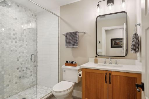 Lower level 3/4 bathroom with hexagon marble tile surround.