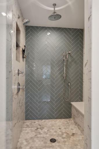 Tile surround walk-in shower with three shower heads.