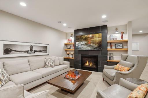 Lower level family room/den with tile surround gas fireplace, built-in storage and white oak shelving.